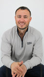 Man wearing a gray sweatshirt with a logo, sitting on a white background