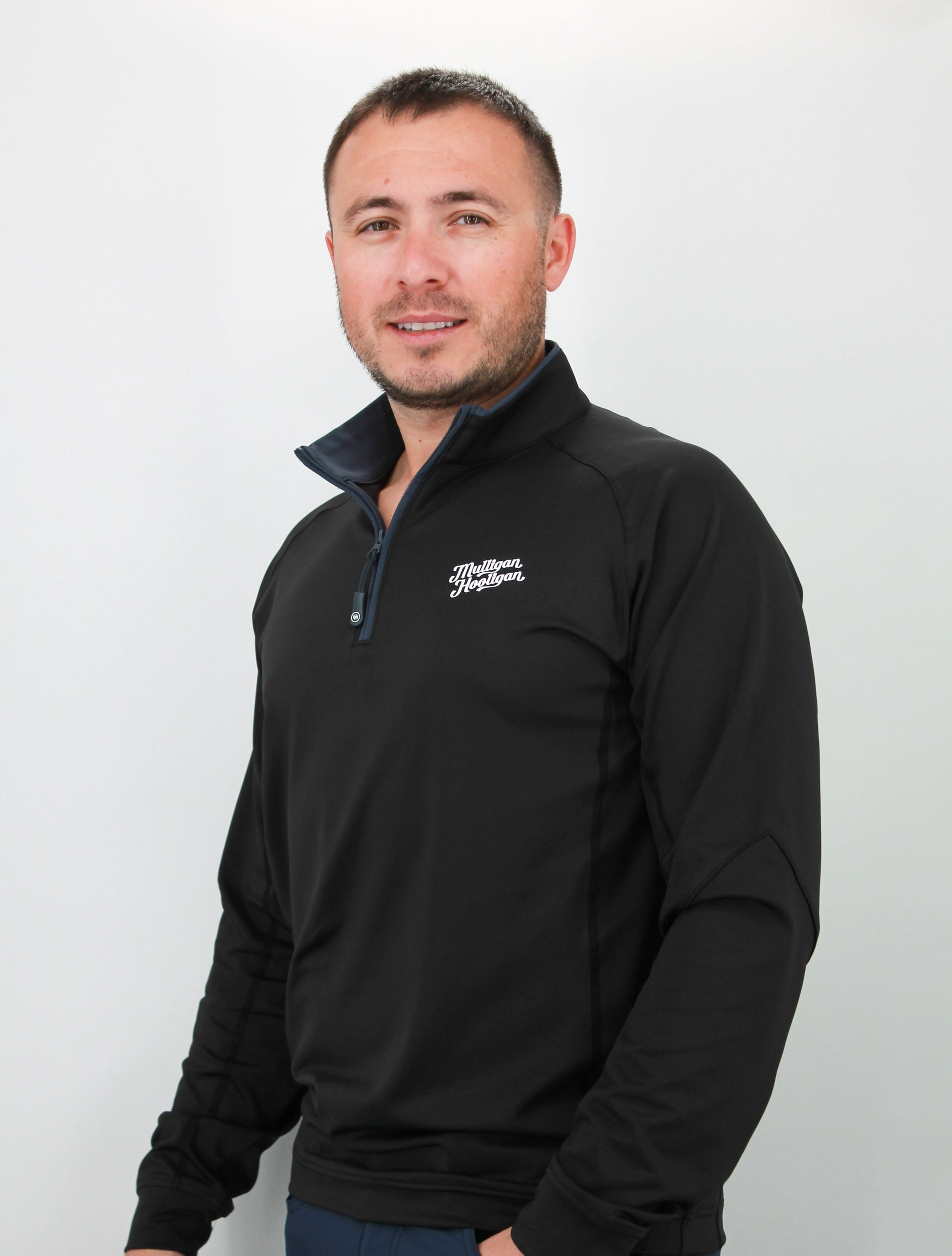 Man wearing a black quarter zip with a logo on a white background